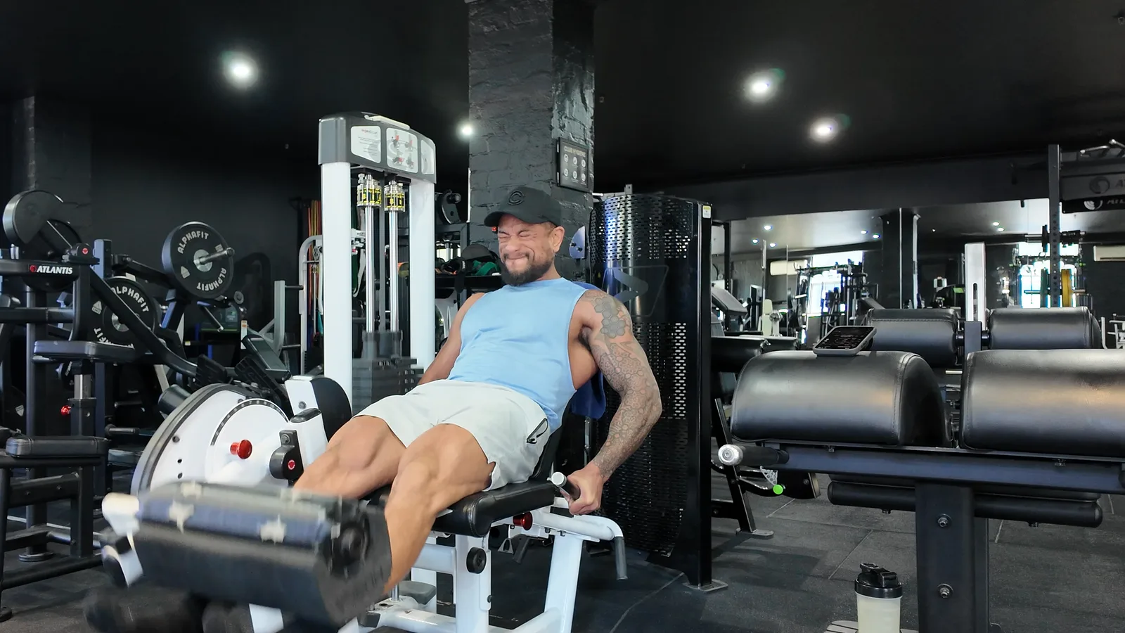 The author mid-rep on a leg extension machine in a commercial gym, face screwed up with effort.